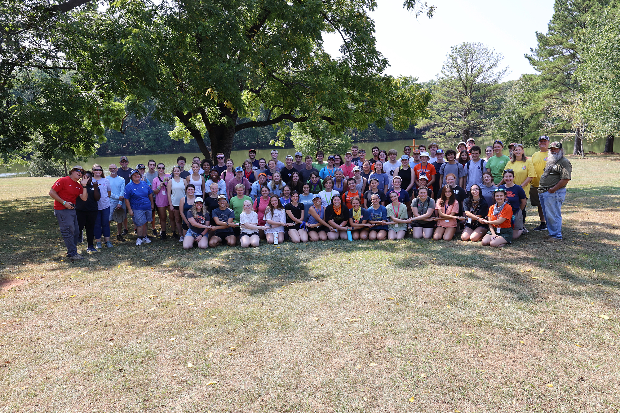 entire group of participants with arms held standing under a huge oak tree on a sunny day